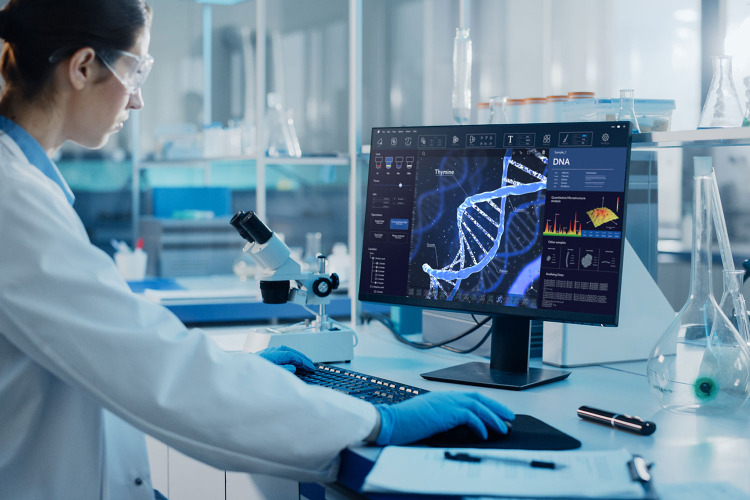 Einblick in ein Labor, in dem eine Frau auf einen Bildschirm mit einer DNA schaut