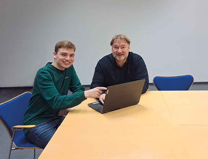 2 Personen an einem Tisch vor einem Laptop sitzend. Sebastian Kampen und Dr. Gerhard Heinzerling.