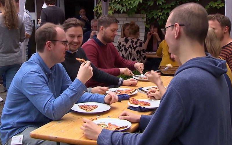 Personen, die am Tisch Pizza essen.