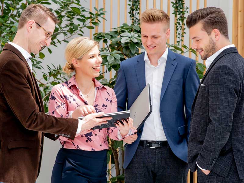 Drei Männer und eine Frau besprechen den Vertriebseinsatz und schauen ihre Opportunities in der SAP Sales Cloud an.