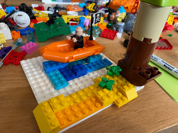 Das perfekte Onboarding, gebaut aus Lego-Steinen. Eine Lego Firgur auf einem Boot.