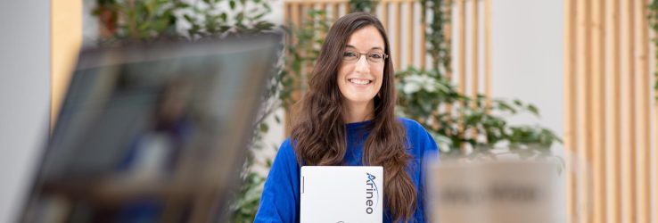 Lächelnde Person mit Laptop in der Hand, plant die Digitalisierung in der Fertigungsindustrie mit Microsoft Dynamics 365
